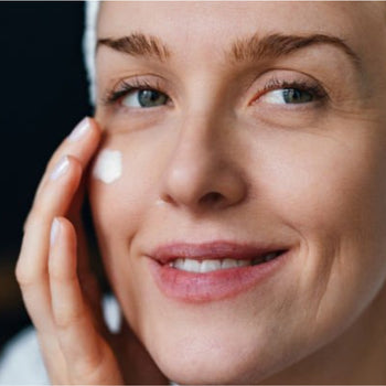 woman putting cream on face smiling